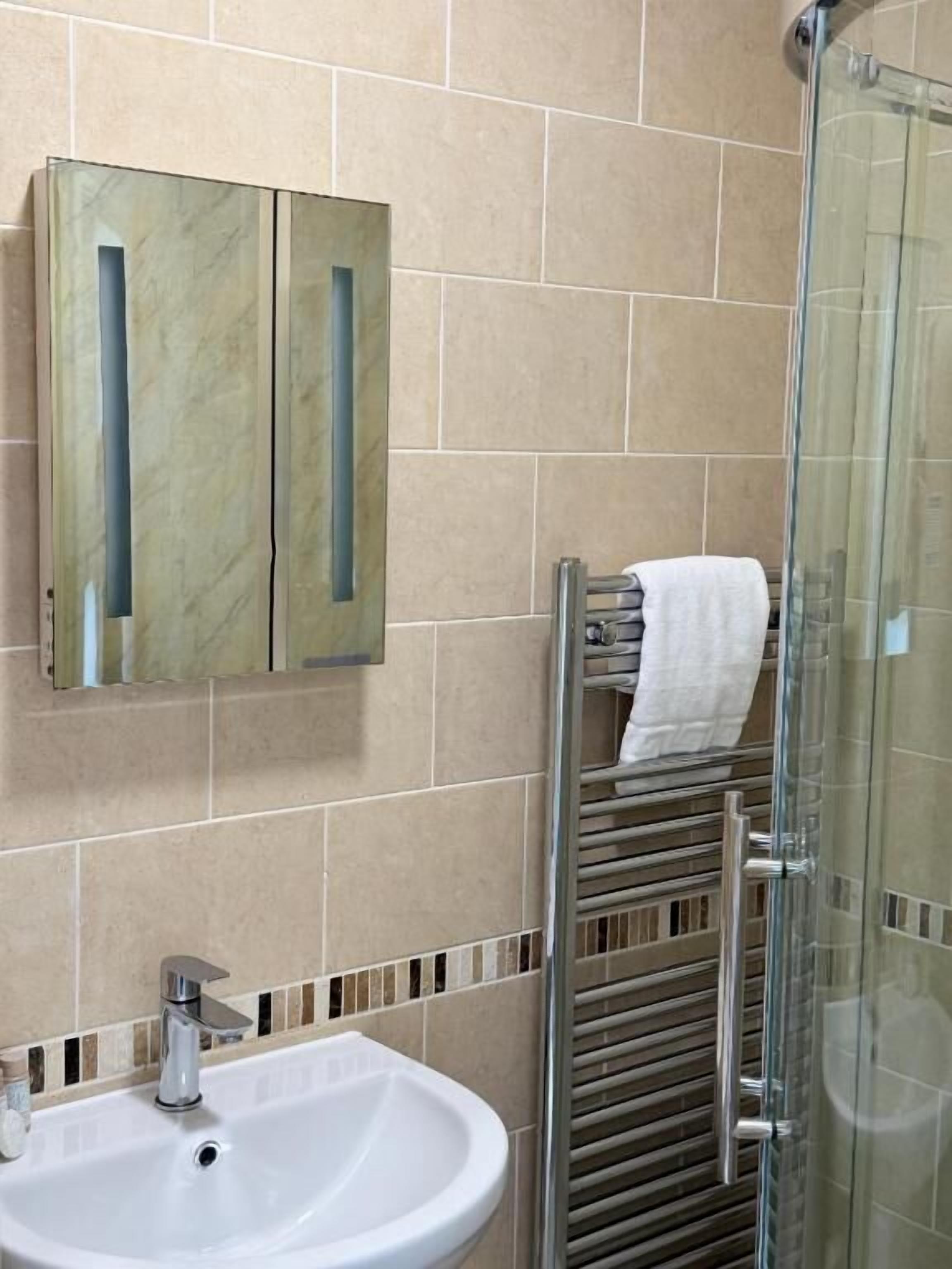 A bathroom with a sink, mirror, and glass shower enclosure.