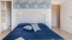 A bedroom with a bed, a headboard, and a wall with a textured pattern. - GuestHost - Family & Friends House - Chic Room (Padova)
