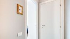 A hallway with a closed door and a framed picture on the wall. - GuestHost - Family & Friends House - Chic Room (Padova)