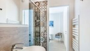 A modern bathroom with a glass shower enclosure, a white sink, and a patterned wall. - GuestHost - Family & Friends House - Chic Room (Padova)