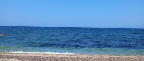 A beach with clear blue water and a sandy shore.