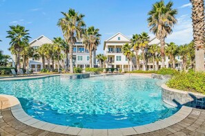 A swimming pool surrounded by palm trees and multi-story buildings with balconies. - Cottages of Romar 7 | Favorite Child | Stunning Beach Front Home with Private Pool! (Orange Beach)