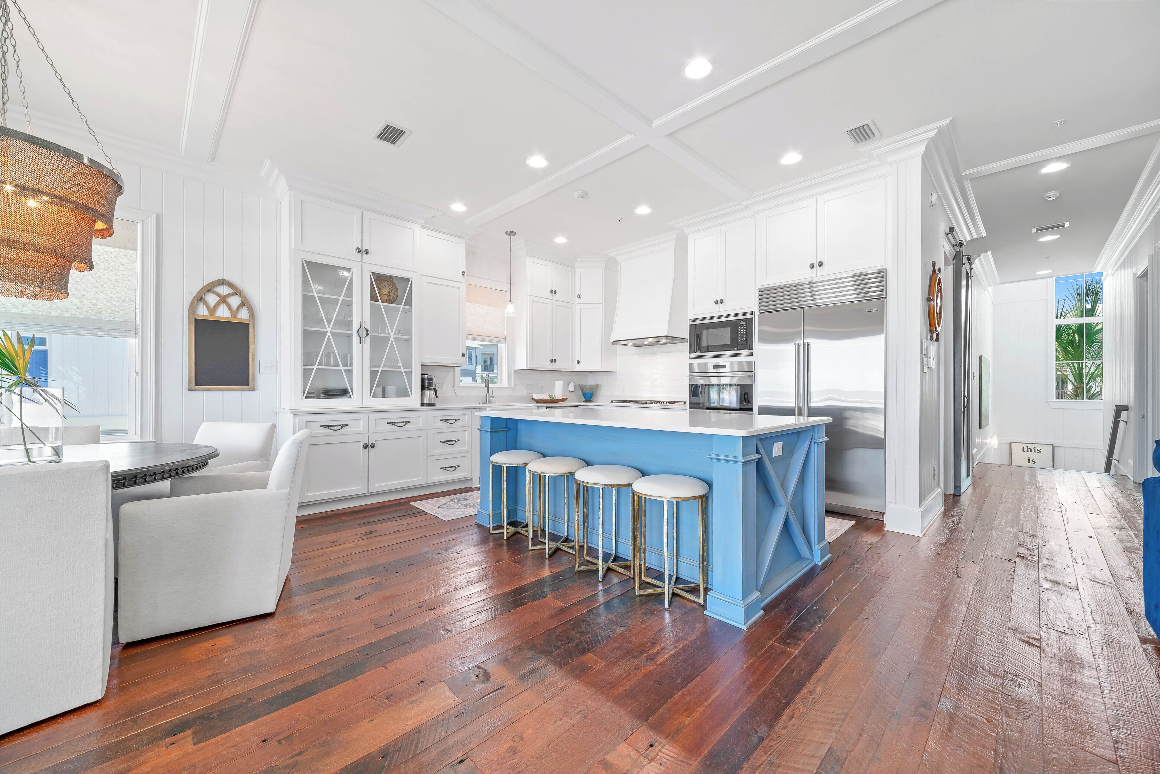 Une cuisine moderne avec des meubles blancs, un îlot central bleu et un plancher en bois.