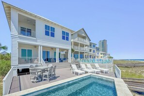 Une propriété en bord de mer, composée de plusieurs étages, dotée d’une piscine, d’un espace extérieur aménagé et offrant une vue sur l’océan.