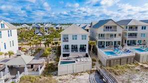 A beachfront property with multiple buildings, a swimming pool, and a covered deck area.