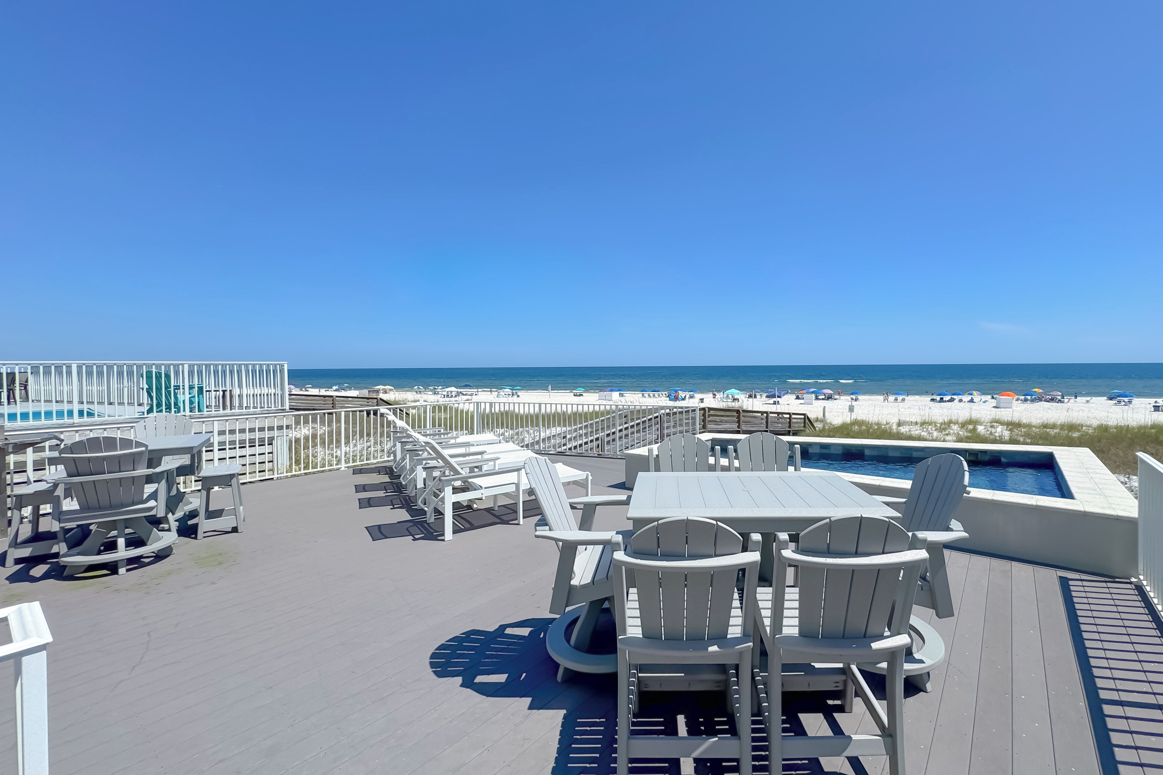A deck with outdoor seating and a pool overlooking a beach.