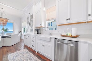 Una cocina moderna con armarios blancos, electrodomésticos de acero inoxidable y vistas al exterior.