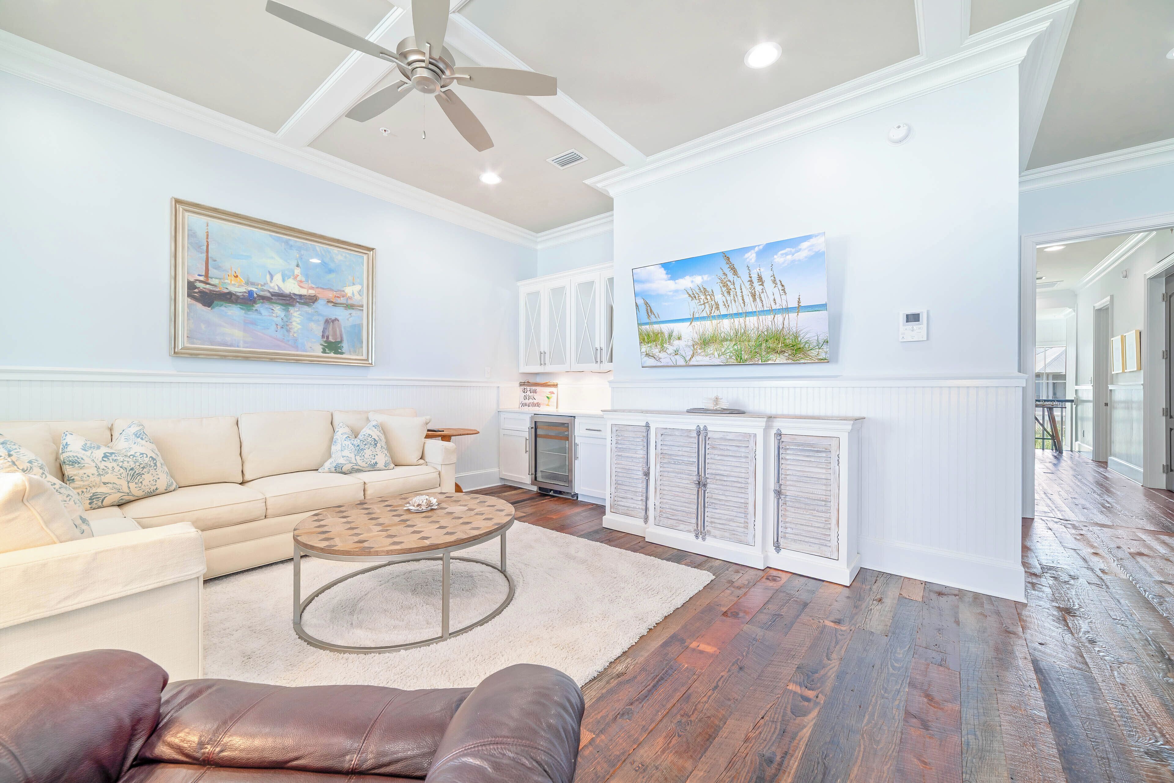 A spacious living room with a high ceiling, a ceiling fan, a fireplace, and a large painting.