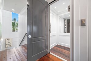 A modern interior with a dark grey door, white walls, and a wooden floor.