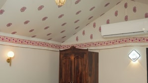 Een kamer met een eettafel, stoelen, een houten kast, een hanglamp en plafondtegels met een patroon.