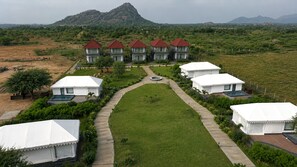 Ein Resort mit mehreren Bungalows, einem zentralen Weg und einem Bergpanorama.
