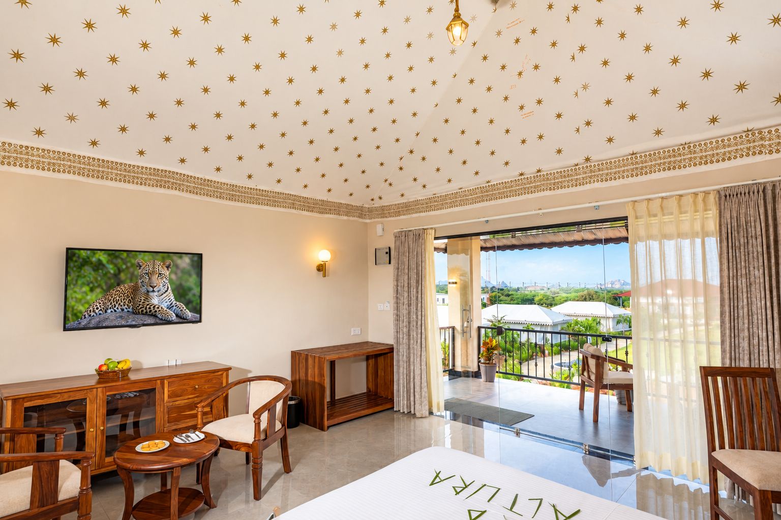 Een hotelkamer met een balkon, een zithoek en een groot raam met uitzicht.