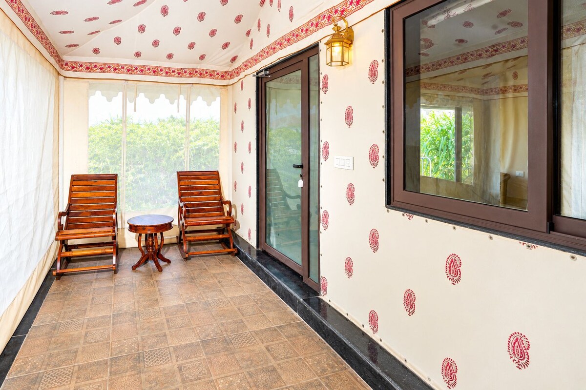 Una habitación con dos sillas de madera, una pequeña mesa, un ventanal corredero y paredes con un diseño.