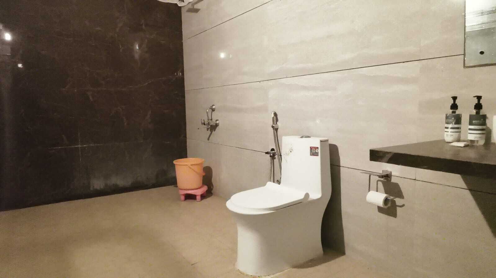 Uma casa de banho com sanita, chuveiro e lavatório.