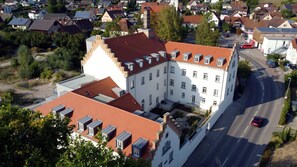 Ein mehrgeschossiges Gebäude mit rotem Ziegeldach, zahlreichen Fenstern und einem Innenhof.