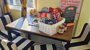 Una habitación con piso a cuadros, una mesa con una cesta de bocadillos, sillas y un letrero con un mensaje.