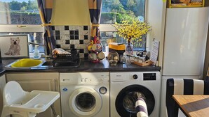 Una cocina compacta con lavadora, un lavabo y una silla.