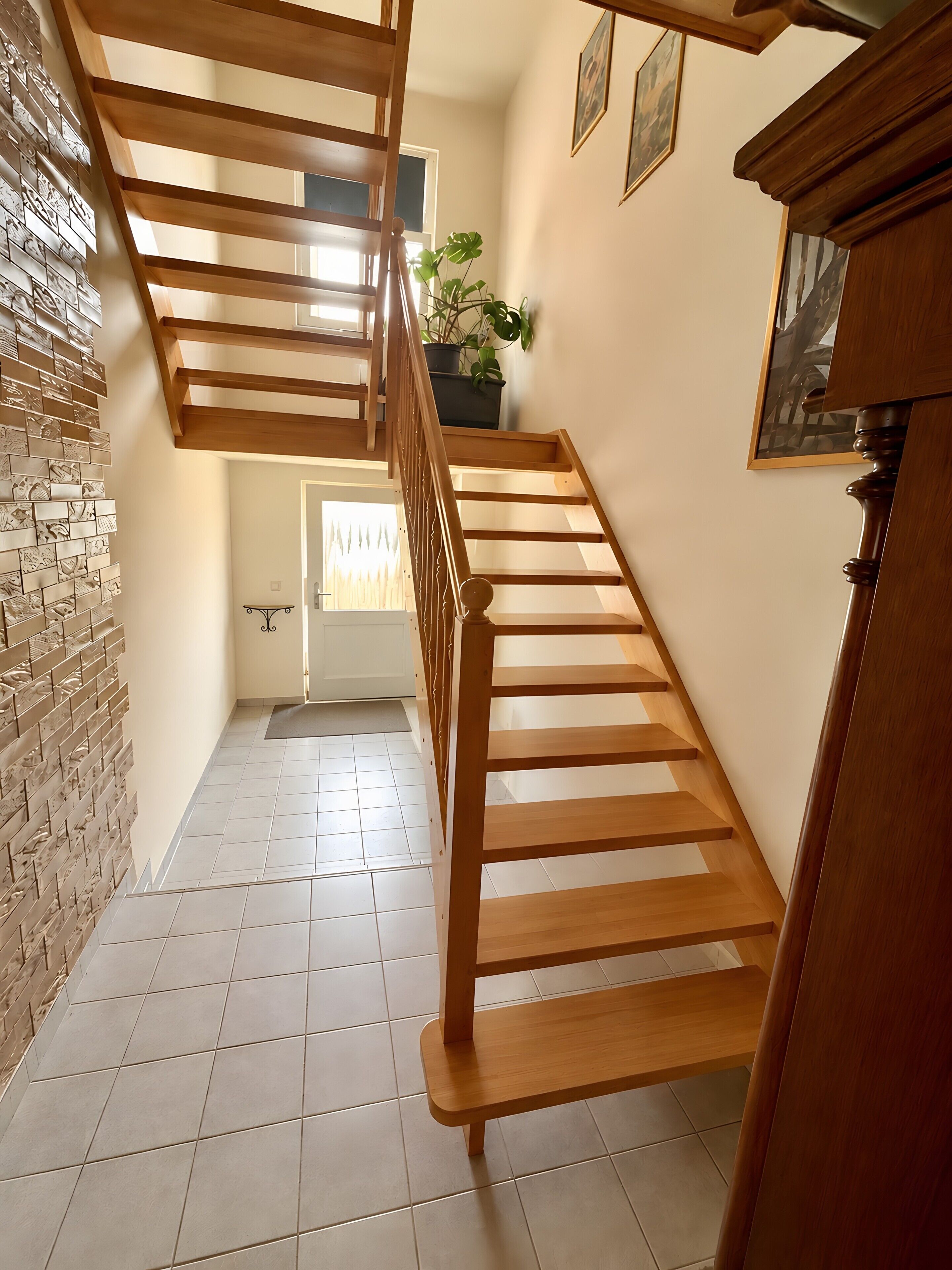 A wooden staircase with a tiled floor leading to a door.