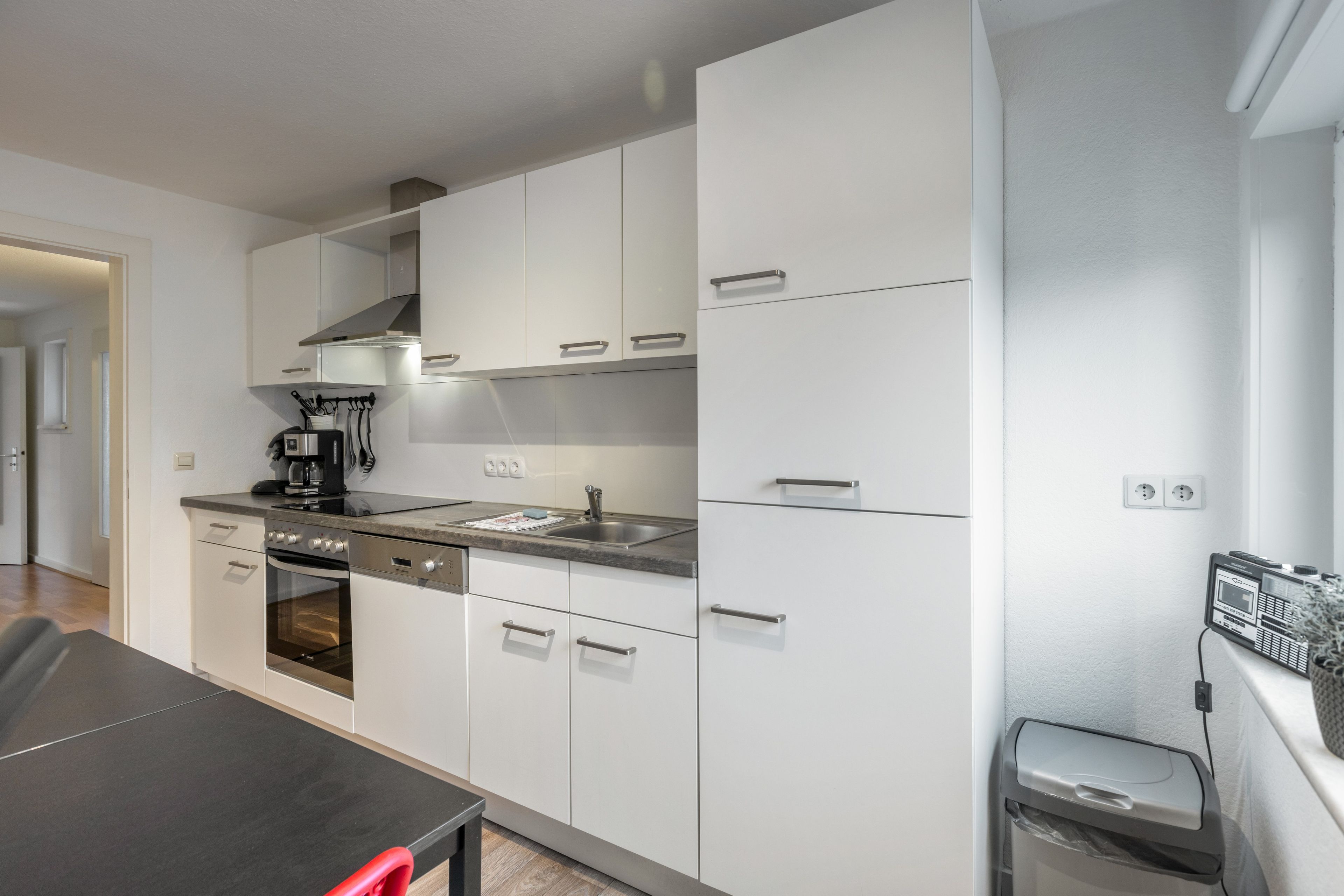 Una cocina moderna con gabinetes blancos, electrodomésticos de acero inoxidable y un horno empotrado.