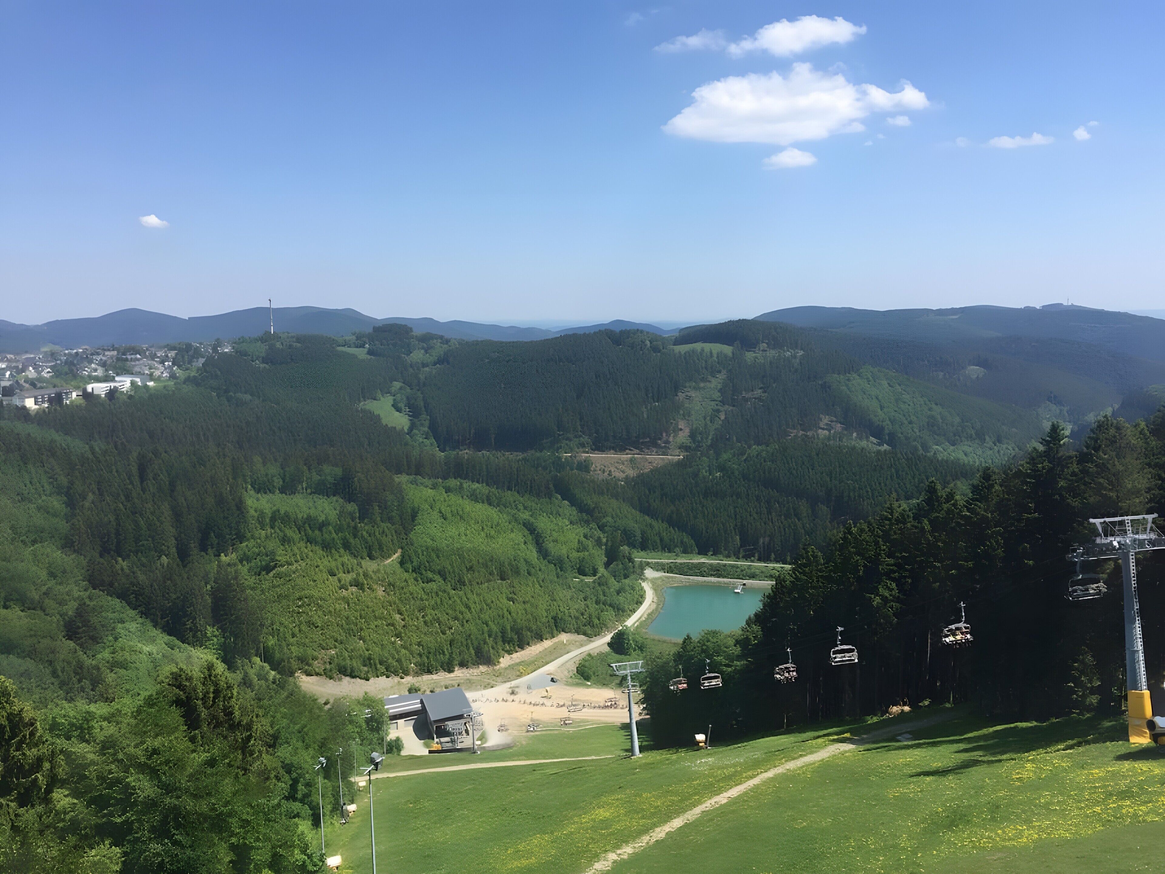 A mountainous landscape with a clear sky, a lake, and a ski lift.