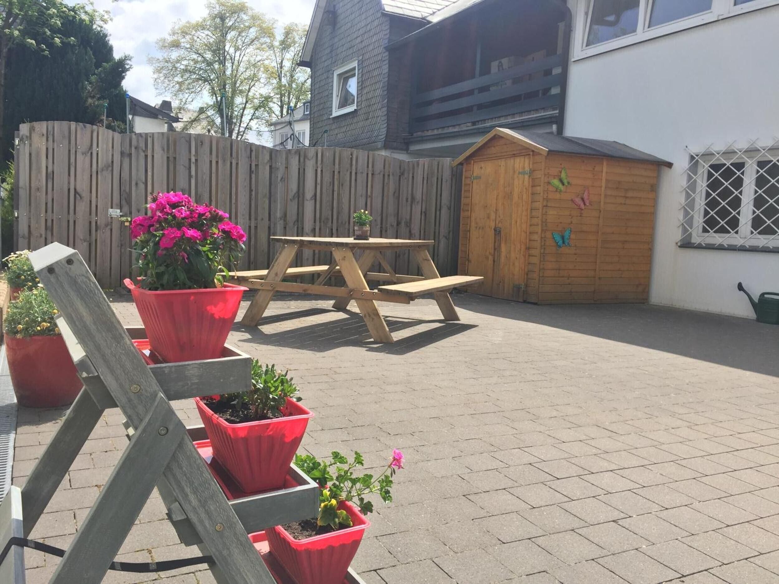 Een houten terras met een picknicktafel en plantenpotten.