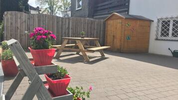 Een houten terras met een picknicktafel en plantenpotten.