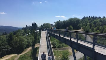 Een voetgangersbrug met een metalen hekwerk, verbinding twee verhoogde delen met een weg eronder.