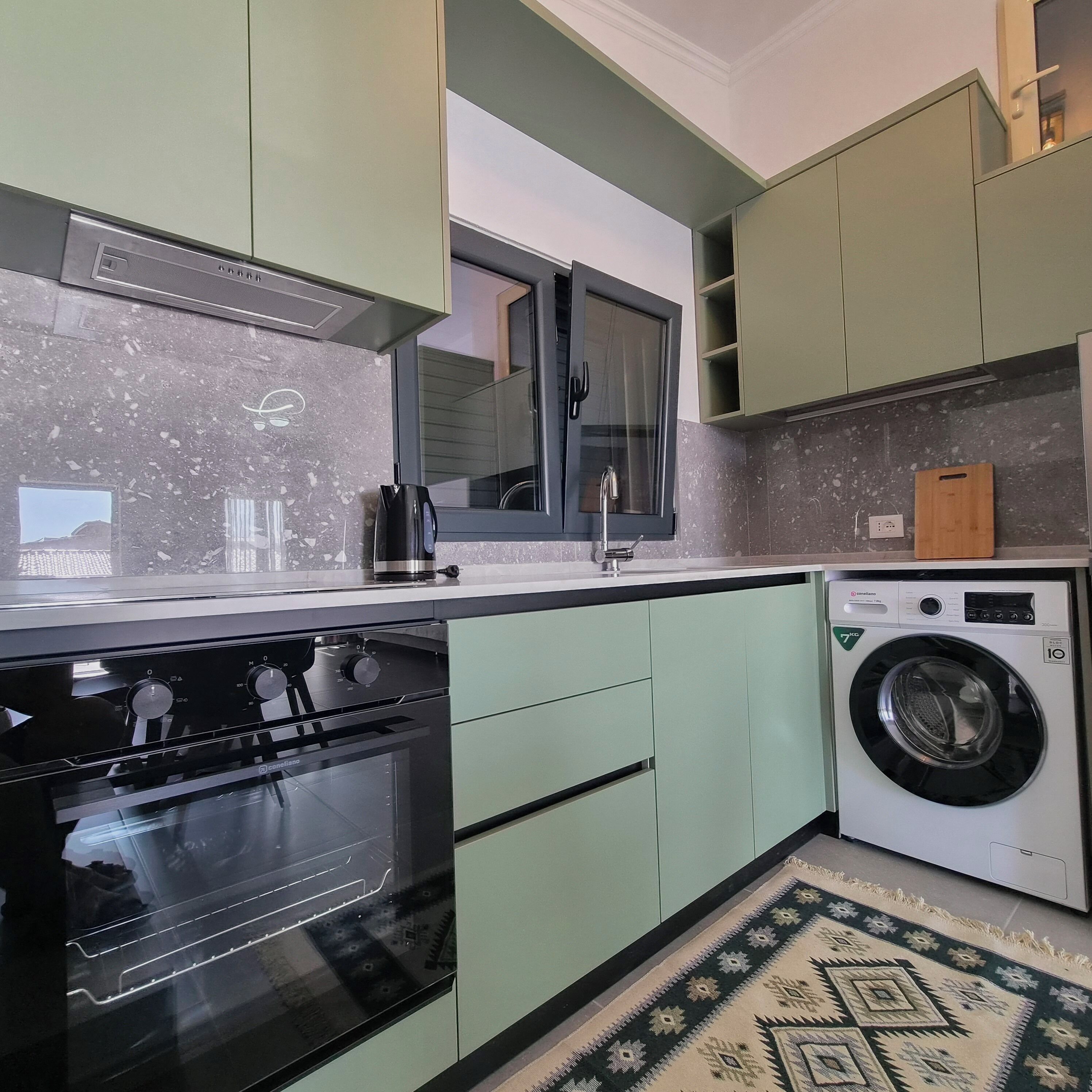 Una cucina con forno a incasso, lavatrice e finestra vista.