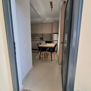 A modern kitchen with a dining area, featuring a table with chairs, a refrigerator, and a microwave. - Kypsel Apartment – Your Cozy Beach Getaway in Durrës (Durrës)