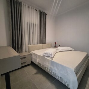 A bedroom with a bed, bedside tables, a lamp, and curtains. - Kypsel Apartment – Your Cozy Beach Getaway in Durrës (Durrës)