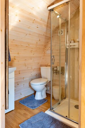 A compact bathroom with a toilet, a shower enclosure, and a sink.