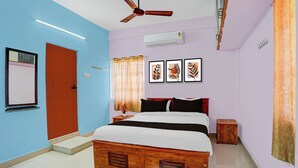 A bedroom with a bed, a ceiling fan, an air conditioning unit, a window with curtains, and framed artwork on the wall. - Collection O Westhill Near Govt Engg (Kozhikode)