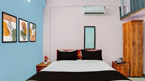 A hotel room with a bed, a wardrobe, a bedside table, a mirror, and wall art. - Collection O Westhill Near Govt Engg (Kozhikode)