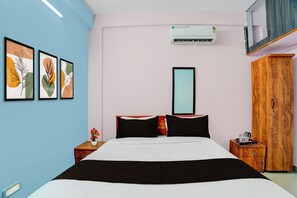 A hotel room with a bed, a wardrobe, a bedside table, a mirror, and wall art. - Collection O Westhill Near Govt Engg (Kozhikode)