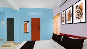 A hotel room with a bed, a door, and a wall with framed artwork. - Collection O Westhill Near Govt Engg (Kozhikode)