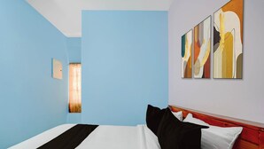 A hotel room with a bed, a headboard, and a wall with abstract art. - Collection O Westhill Near Govt Engg (Kozhikode)