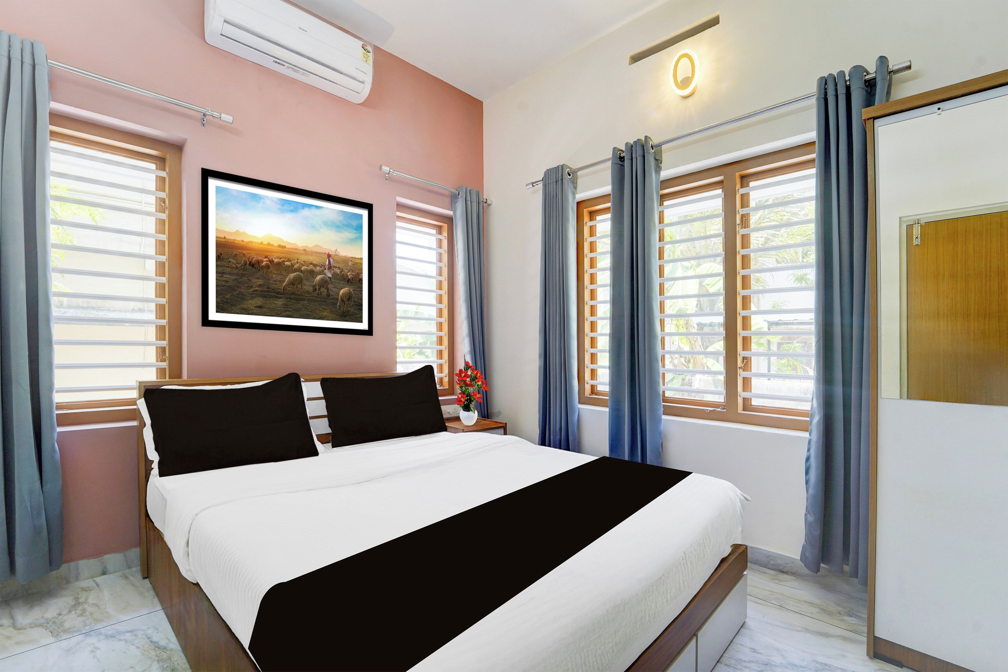 Una habitación de hotel con una cama, un cuadro, aire acondicionado y una ventana con cortinas.