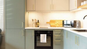 Una cucina con forno a incasso, microonde e bollitore sul piano di lavoro.