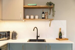 A kitchen with a black faucet, a wine bottle, and a glass on the counter. - Pelican House One | Luxury Apartment | 6 Min Walk to Beach | Bournemouth Centre (Bournemouth)