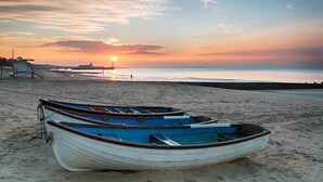 Una spiaggia con barche e un molo sullo sfondo.
