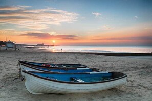 Ein Strand mit Booten und einer Pier im Hintergrund.