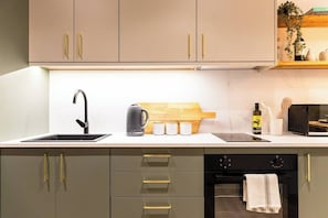A modern kitchen with a sink, kettle, microwave, and oven. - Pelican House One | Luxury Apartment | 6 Min Walk to Beach | Bournemouth Centre (Bournemouth)