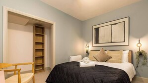 Una camera da letto con un letto, una sedia, una libreria e un termosifone.