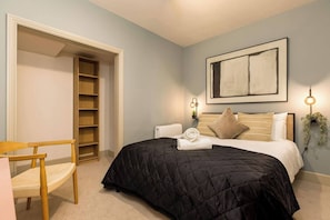 Ein Schlafzimmer mit einem Bett, einem Sessel, einem Bücherregal und einer Heizung.