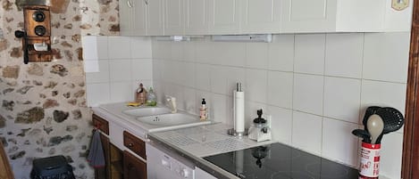 Eine Küche mit weißen Schränken, einer schwarzen Arbeitsplatte und einer Steinwand.
