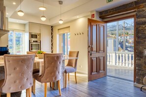 Eine moderne Küche mit integrierten Geräten, ein Essbereich mit gepolsterten Stühlen und ein Balkon mit Steinwand.