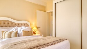 A hotel room with a large bed, a bedside table with a lamp, and a door. - Casa São Tiago, a Home in Madeira (Ponta do Sol)