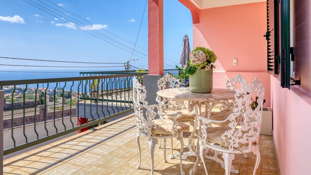 A balcony with a table and chairs, a potted plant, and a view of the sea. - Sunrise House, a Home in Madeira (Ponta do Sol)
