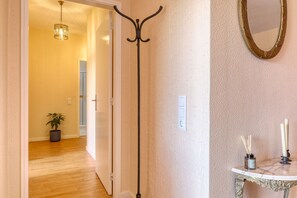 A hallway with a coat rack, a potted plant, a mirror, and a table with candles. - Sunrise House, a Home in Madeira (Ponta do Sol)