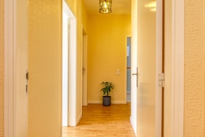 A hallway with wooden flooring and yellow walls, leading to a room with a door. - Sunrise House, a Home in Madeira (Ponta do Sol)